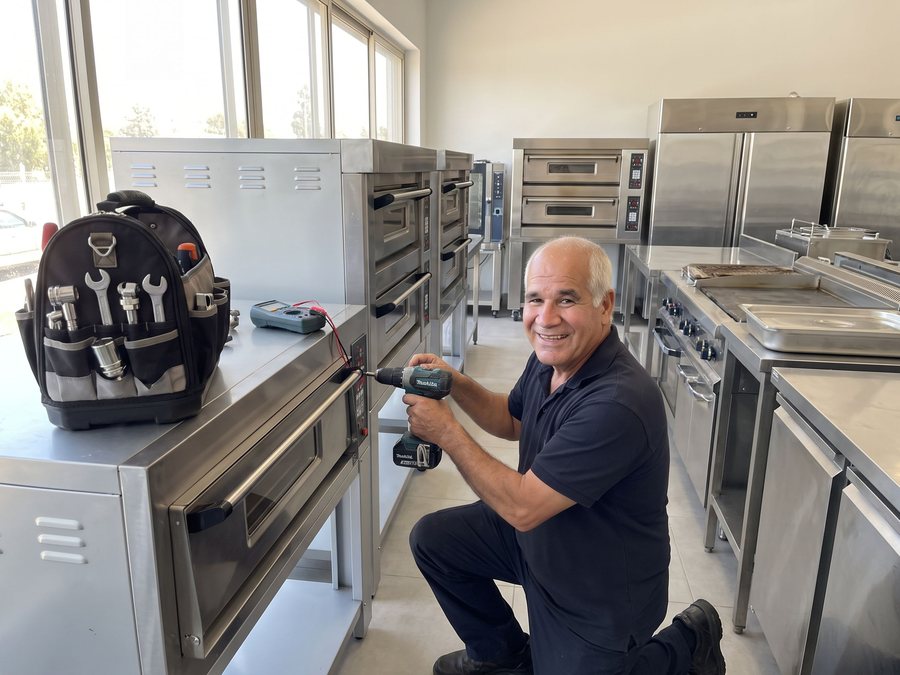 איש כל בודק בודק תנור פיצה באולם תצוגה של ציוד מטבח חדש ומשומש